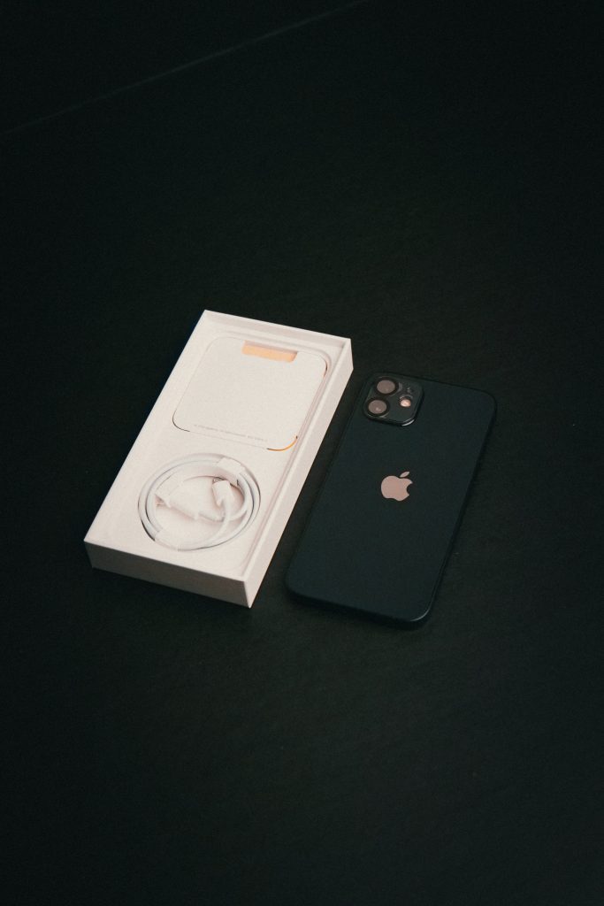 boite neuve iphone avec cable inclu et smartphone posé à côté sur fond noir