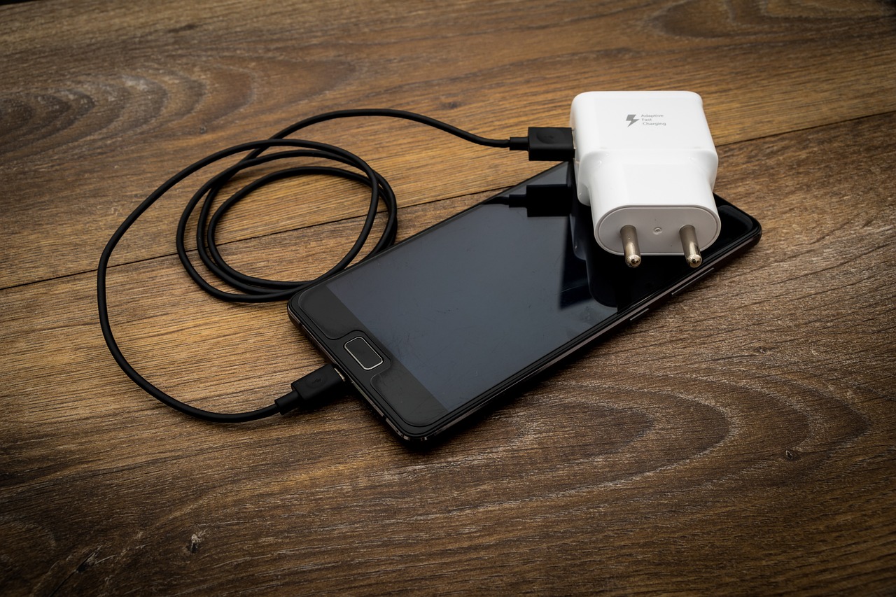 chargeur avec cable synthétique branché à un smartphone posé sur une table en bois